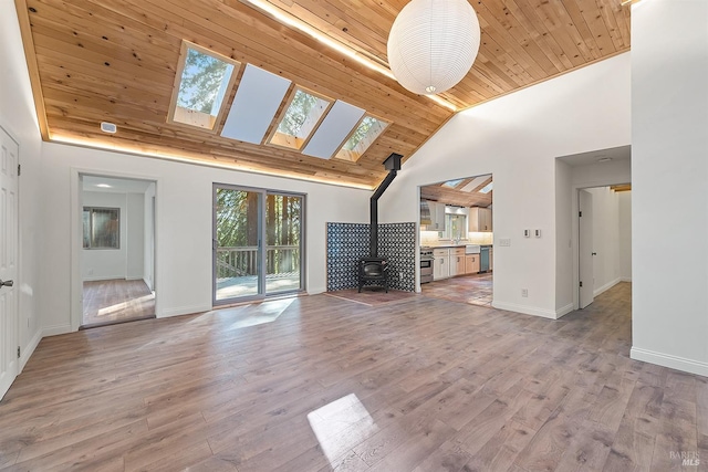 17075 Fitzpatrick Ln, Occidental, CA 95465 - unfurnished living room with a wood stove, wooden ceiling, a skylight, high vaulted ceiling, and baseboards