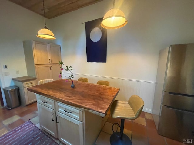 17075 Fitzpatrick Ln, Occidental, CA 95465 - kitchen featuring freestanding refrigerator, a wainscoted wall, butcher block counters, pendant lighting, and a breakfast bar