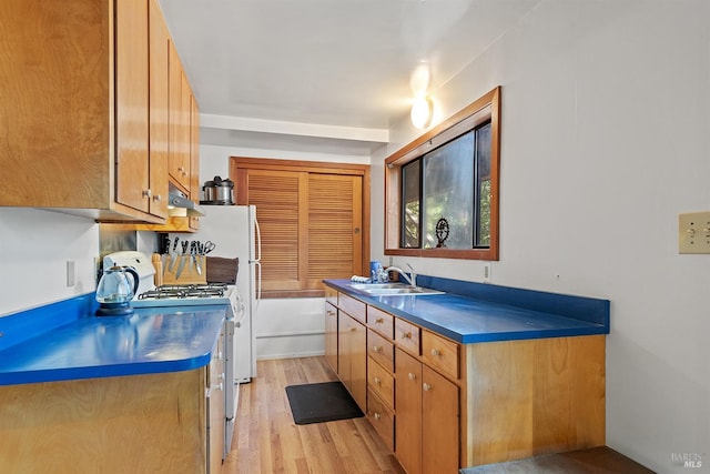 17075 Fitzpatrick Ln, Occidental, CA 95465 - kitchen featuring a sink, white range with gas stovetop, under cabinet range hood, light wood finished floors, and brown cabinets