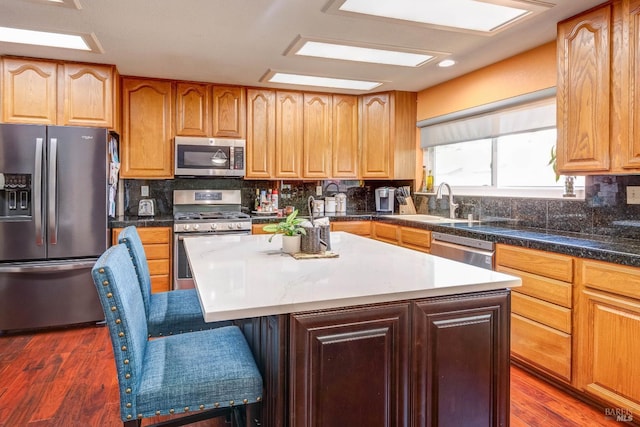 32 Romine Way, Vallejo, CA 94591 - kitchen featuring appliances with stainless steel finishes, a breakfast bar, decorative backsplash, a kitchen island, and dark wood-type flooring