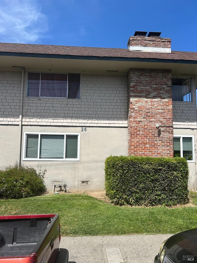 26 Fairfax Unit C, San Rafael, CA 94901 - view of home's exterior with brick siding, a chimney, stucco siding, and a lawn