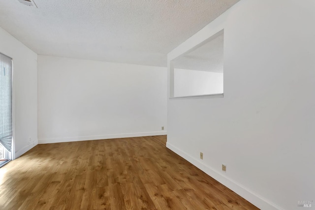 spare room with wood finished floors, baseboards, and a textured ceiling