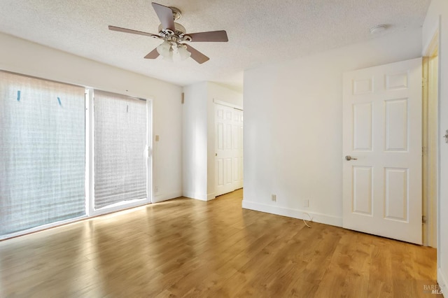 spare room featuring ceiling fan, a textured ceiling, light wood-type flooring, baseboards, and a smoke detector