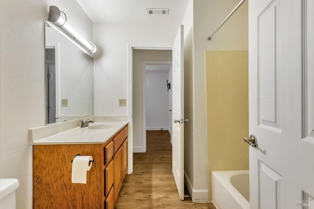bathroom with vanity, wood finished floors, toilet, and tub / shower combination