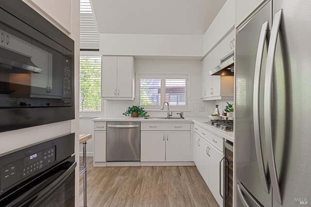 44 Lagoon Vis, Tiburon, CA 94920 - kitchen featuring appliances with stainless steel finishes, under cabinet range hood, a sink, tasteful backsplash, and light wood finished floors