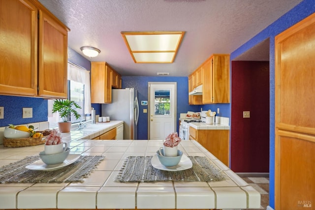 766 Morissette Way, Vacaville, CA 95687 - kitchen with tile countertops, under cabinet range hood, white gas range, freestanding refrigerator, and a sink