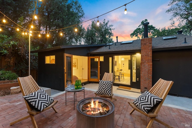 back of property at dusk with a fire pit, a patio, and a chimney