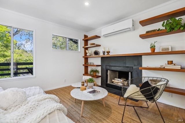 living area featuring a wall mounted AC, a fireplace, plenty of natural light, wood finished floors, and ornamental molding