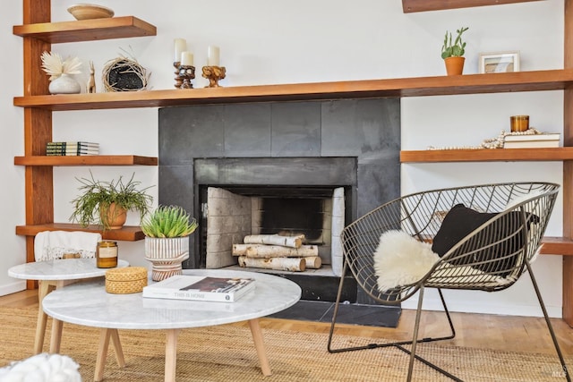 living area featuring wood finished floors, a tiled fireplace, and baseboards