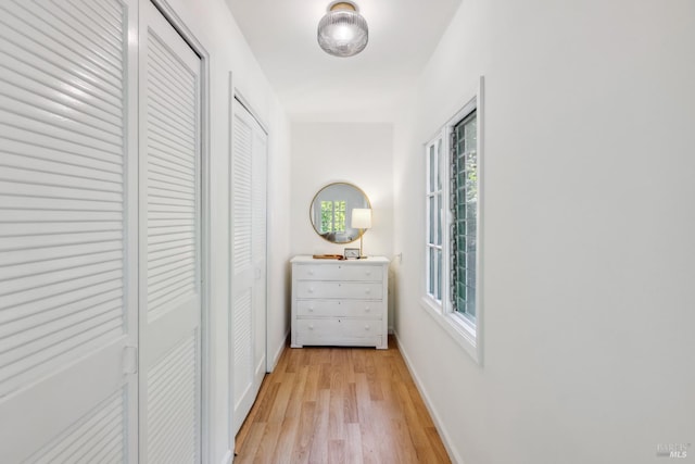 corridor with light wood-style flooring and baseboards