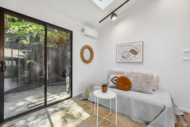 sitting room with a skylight, a wall unit AC, wood finished floors, lofted ceiling, and baseboards