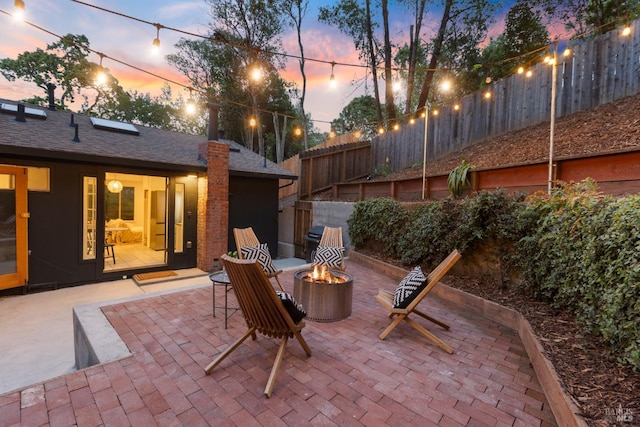 patio terrace at dusk featuring a fire pit and fence