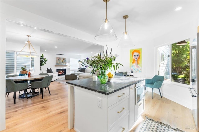 1358 Sylvan Ct, Healdsburg, CA 95448 - kitchen with light wood-style floors, a lit fireplace, white cabinetry, hanging light fixtures, and recessed lighting