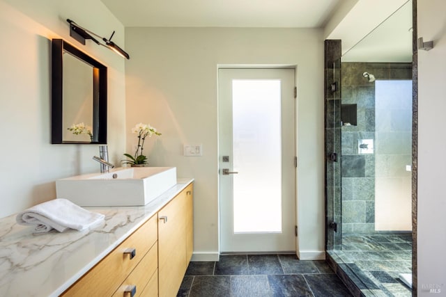 8909 Mill Creek Rd, Healdsburg, CA 95448 - bathroom featuring a tile shower, vanity, baseboards, and stone finish floors