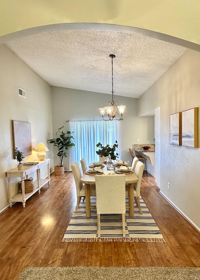 3 Clemson Ct, Woodland, CA 95695 - dining room with wood finished floors, a chandelier, a textured ceiling, lofted ceiling, and baseboards