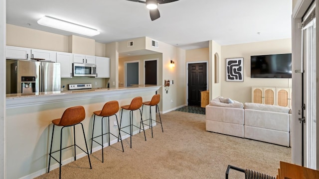 4200 E Commerce Way Unit 1324, Sacramento, CA 95834 - kitchen with stainless steel appliances, light colored carpet, a kitchen bar, ceiling fan, and white cabinetry