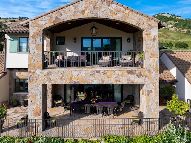 7035 Silverado Trl, Napa, CA 94558 - rear view of property featuring a balcony, an outdoor stone fireplace, a patio, and stucco siding