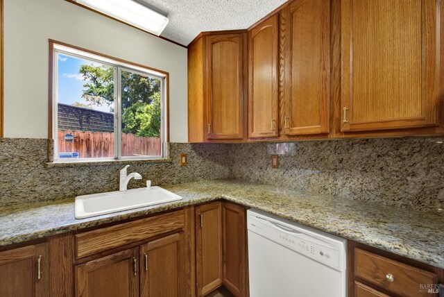 970 El Camino Ave Unit 3, Vacaville, CA 95688 - kitchen with white dishwasher, a sink, decorative backsplash, brown cabinets, and a textured ceiling