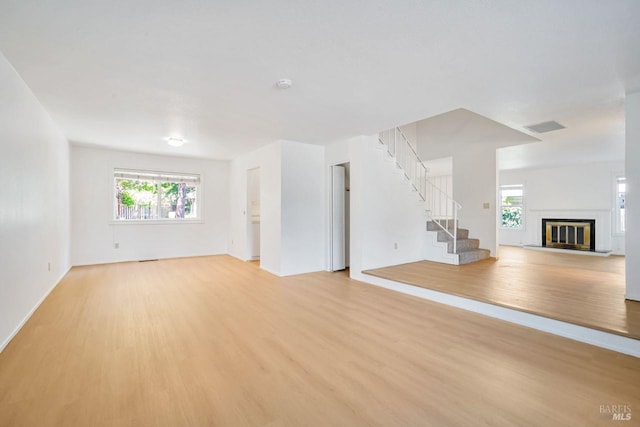 5705 Dexter Cir, Rohnert Park, CA 94928 - unfurnished living room featuring light wood finished floors, stairs, a glass covered fireplace, and baseboards