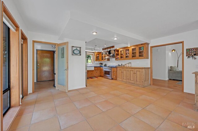 7293 Occidental Rd, Sebastopol, CA 95472 - kitchen with high end range, brown cabinets, glass insert cabinets, and light countertops