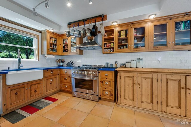 7293 Occidental Rd, Sebastopol, CA 95472 - kitchen with high end range, a sink, backsplash, wall chimney exhaust hood, and light tile patterned floors