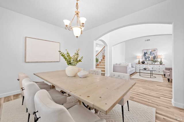 201 Red Pheasant Dr, Vacaville, CA 95687 - dining room with arched walkways, light wood-type flooring, stairs, a chandelier, and baseboards