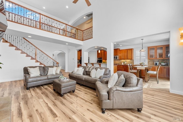 201 Red Pheasant Dr, Vacaville, CA 95687 - living area with arched walkways, light wood-style floors, a ceiling fan, baseboards, and a towering ceiling