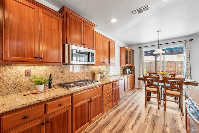 201 Red Pheasant Dr, Vacaville, CA 95687 - kitchen featuring appliances with stainless steel finishes, light wood finished floors, brown cabinetry, decorative backsplash, and decorative light fixtures