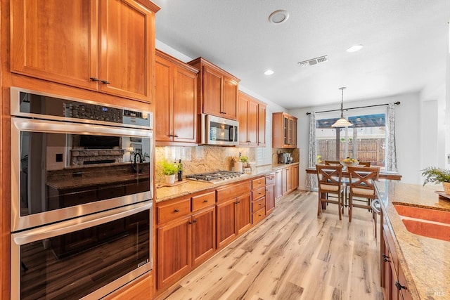 201 Red Pheasant Dr, Vacaville, CA 95687 - kitchen featuring stainless steel appliances, light wood finished floors, light stone countertops, backsplash, and brown cabinets