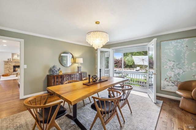 9724 Green Valley Rd, Sebastopol, CA 95472 - dining space featuring ornamental molding, a chandelier, wood finished floors, baseboards, and a stone fireplace