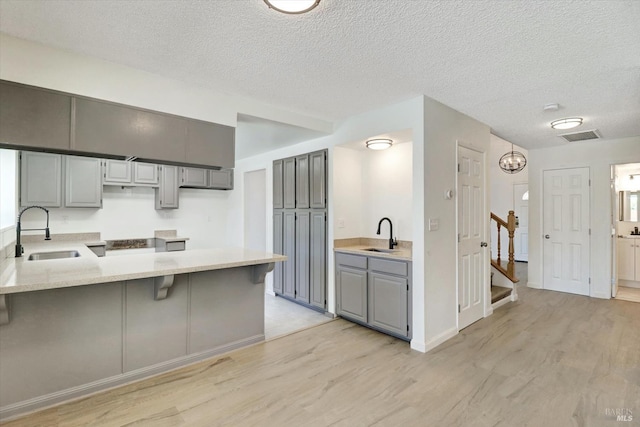 181 Belvedere Ct, Vallejo, CA 94589 - kitchen with a sink, a peninsula, light wood finished floors, gray cabinets, and a textured ceiling