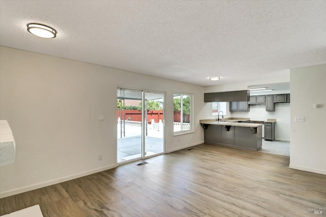 181 Belvedere Ct, Vallejo, CA 94589 - kitchen with a peninsula, a textured ceiling, light wood-style flooring, baseboards, and a kitchen bar