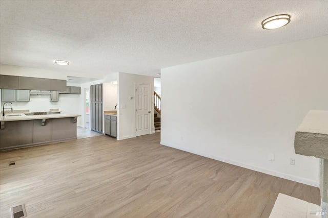181 Belvedere Ct, Vallejo, CA 94589 - unfurnished living room featuring light wood-style floors, a sink, stairs, baseboards, and a textured ceiling