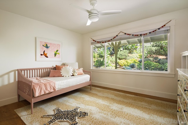 bedroom featuring baseboards, wood finished floors, and a ceiling fan