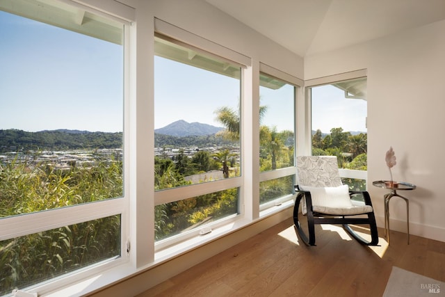 sunroom with a mountain view, wood finished floors, and vaulted ceiling