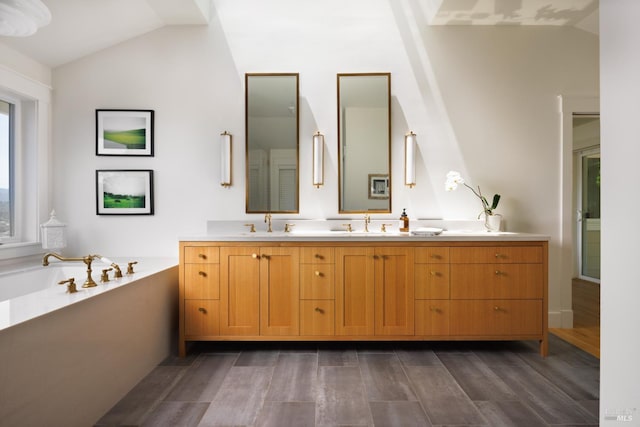 full bath with vaulted ceiling, wood finished floors, a garden tub, and double vanity