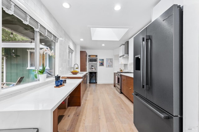 4512 Dry Creek Rd, Napa, CA 94558 - kitchen featuring appliances with stainless steel finishes, modern cabinets, a skylight, wall chimney range hood, and light countertops