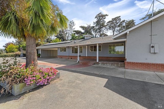 4335 Bodega Ave, Petaluma, CA 95942 - view of front of property featuring solar panels, a porch, roof with shingles, a carport, and brick siding