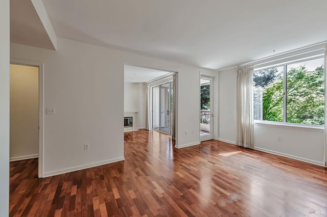 600 Deer Valley Rd Unit 1E, San Rafael, CA 94903 - empty room featuring a glass covered fireplace, wood finished floors, and baseboards
