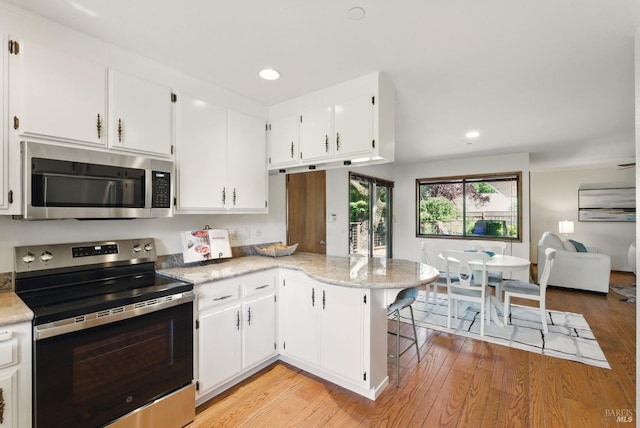 4620 Morris Ct, Santa Rosa, CA 95405 - kitchen with stainless steel appliances, a peninsula, light wood-style floors, white cabinets, and recessed lighting
