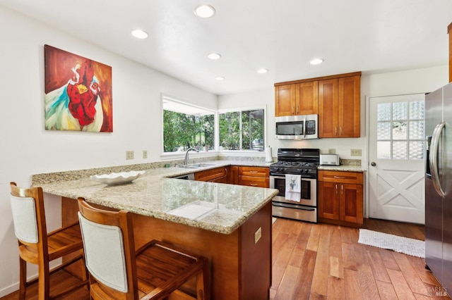 4100 Petrified Forest Rd, Santa Rosa, CA 94515 - kitchen featuring appliances with stainless steel finishes, a peninsula, brown cabinets, light stone countertops, and recessed lighting