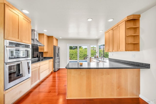 3730 Ruston Ln, Napa, CA 94558 - kitchen with wall chimney range hood, appliances with stainless steel finishes, light brown cabinets, a peninsula, and wood finished floors