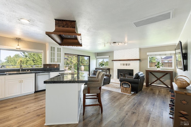 10505 Cherry Ridge Rd, Sebastopol, CA 95472 - kitchen featuring stainless steel dishwasher, a sink, white cabinetry, a kitchen bar, and a kitchen island