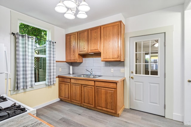 24 S University St, Healdsburg, CA 95448 - kitchen with light countertops, a chandelier, light wood-style flooring, a sink, and brown cabinets