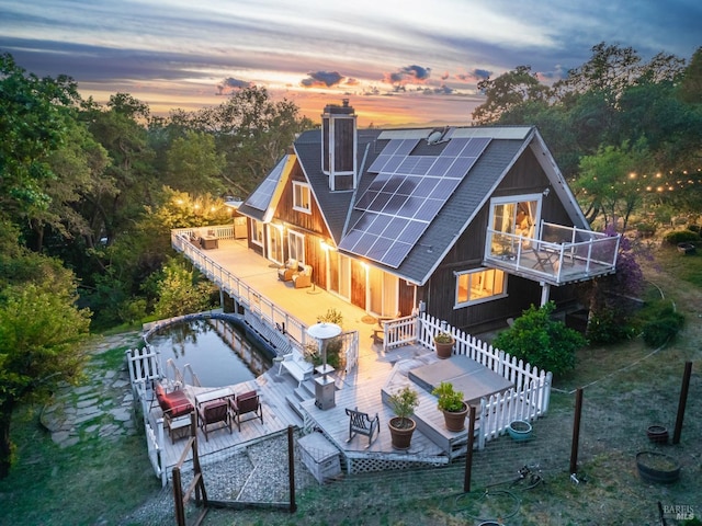 1114 Mount George Ave, Napa, CA 94558 - back of house at dusk with a chimney, solar panels, a deck, and roof with shingles