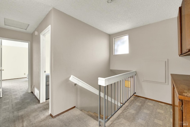 3265 Arroyo Dr, Fairfield, CA 94533 - hallway with an upstairs landing, light colored carpet, a textured ceiling, baseboards, and attic access