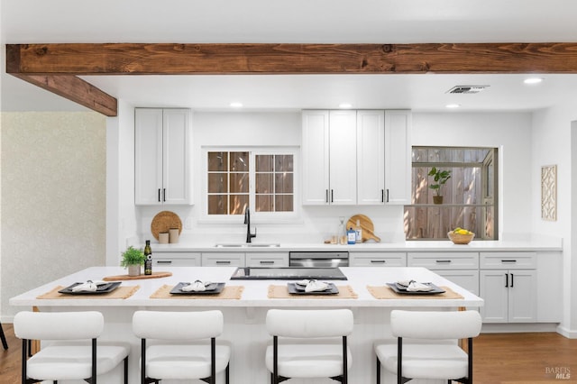 1109 Broadmoor Dr, Napa, CA 94558 - kitchen with a sink, a kitchen bar, light wood-style flooring, white cabinets, and beam ceiling