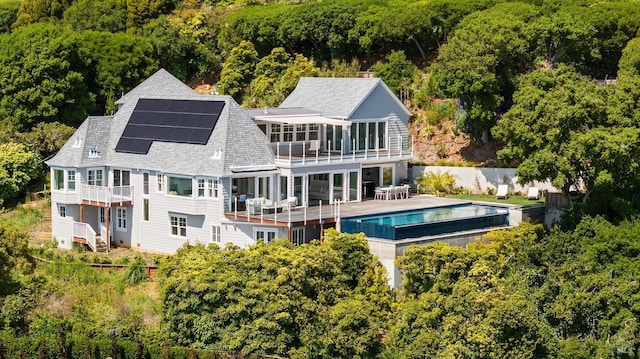 22 Eucalyptus Rd, Belvedere, CA 94920 - rear view of property featuring roof mounted solar panels, a balcony, a forest view, and roof with shingles