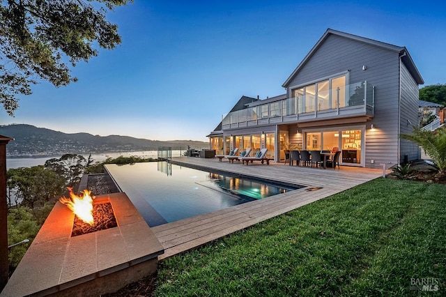 22 Eucalyptus Rd, Belvedere, CA 94920 - rear view of property with a balcony, a fire pit, a yard, a pool with connected hot tub, and a deck with mountain view