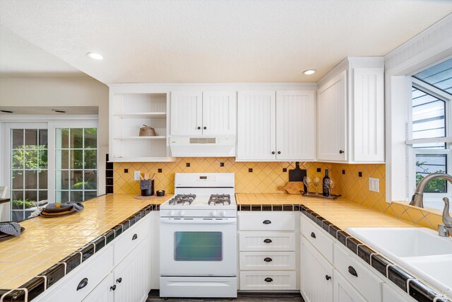 632 E K St, Benicia, CA 94510 - kitchen featuring white range with gas cooktop, under cabinet range hood, a sink, white cabinetry, and tasteful backsplash